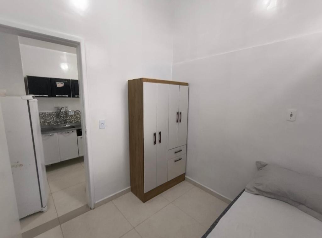a white room with a cabinet and a kitchen at kitnet Próximo ao Metro Conceição in Sao Paulo