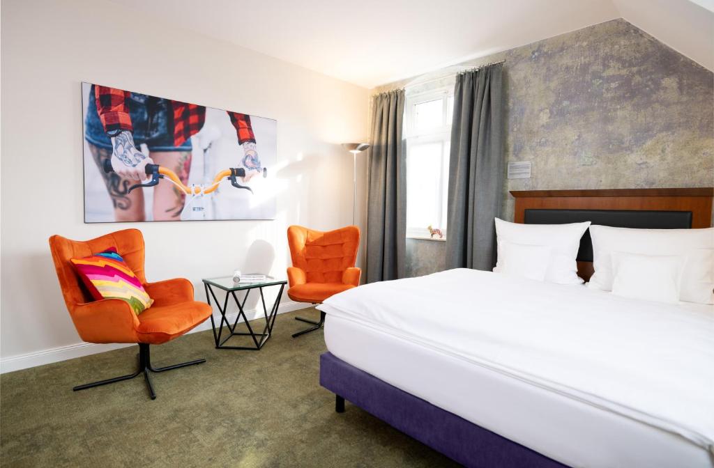 Una habitación de hotel con una cama y dos sillas. en Kochs Stadthotel, en Olpe