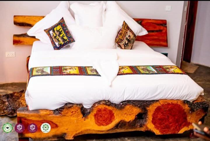 een bed met witte lakens en kussens in een kamer bij Twalumba Resort & Village in Mwanachunga