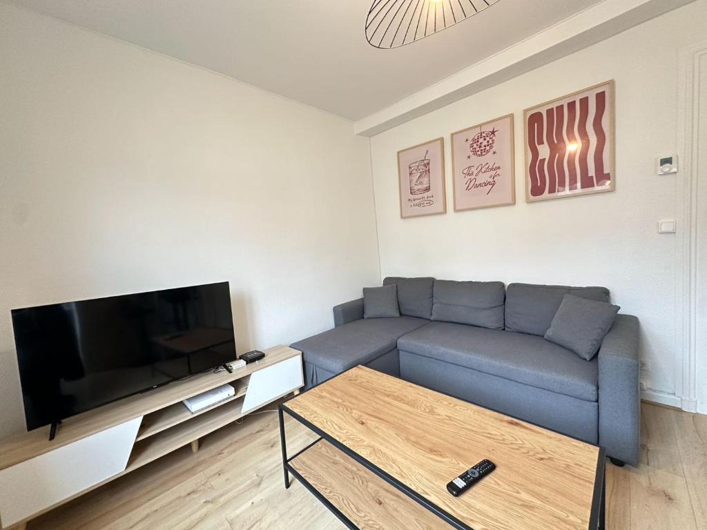 un salon avec un canapé bleu et une télévision à écran plat dans l'établissement Las Vegas - appartement à Reims, à Reims