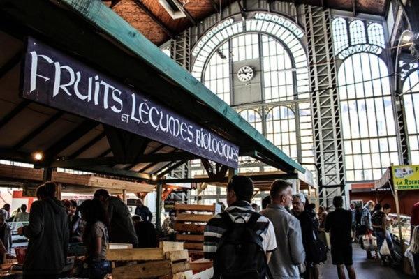 un grupo de personas en un mercado con un reloj en Le Comte - Studio, en Belfort