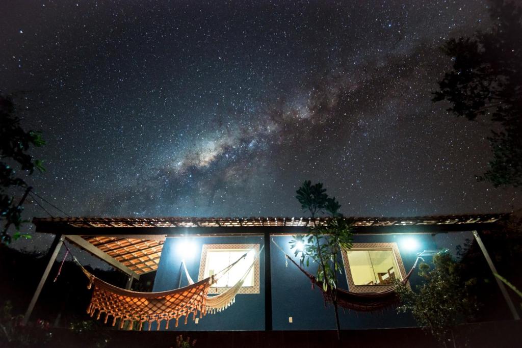 a house with a hammock in front of a starry sky at Pousada Bela Vista do Capão in Palmeiras