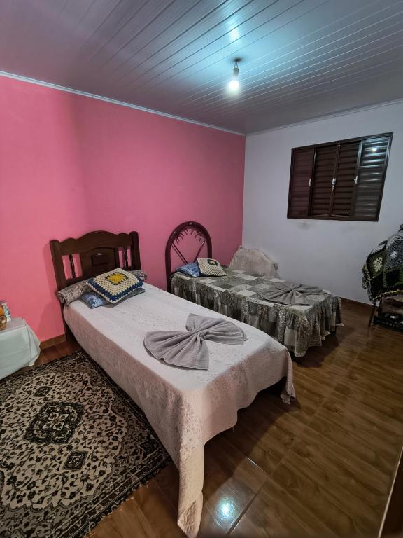 two beds in a room with pink walls at Rancho Pé da Pedra in São Bento do Sapucaí