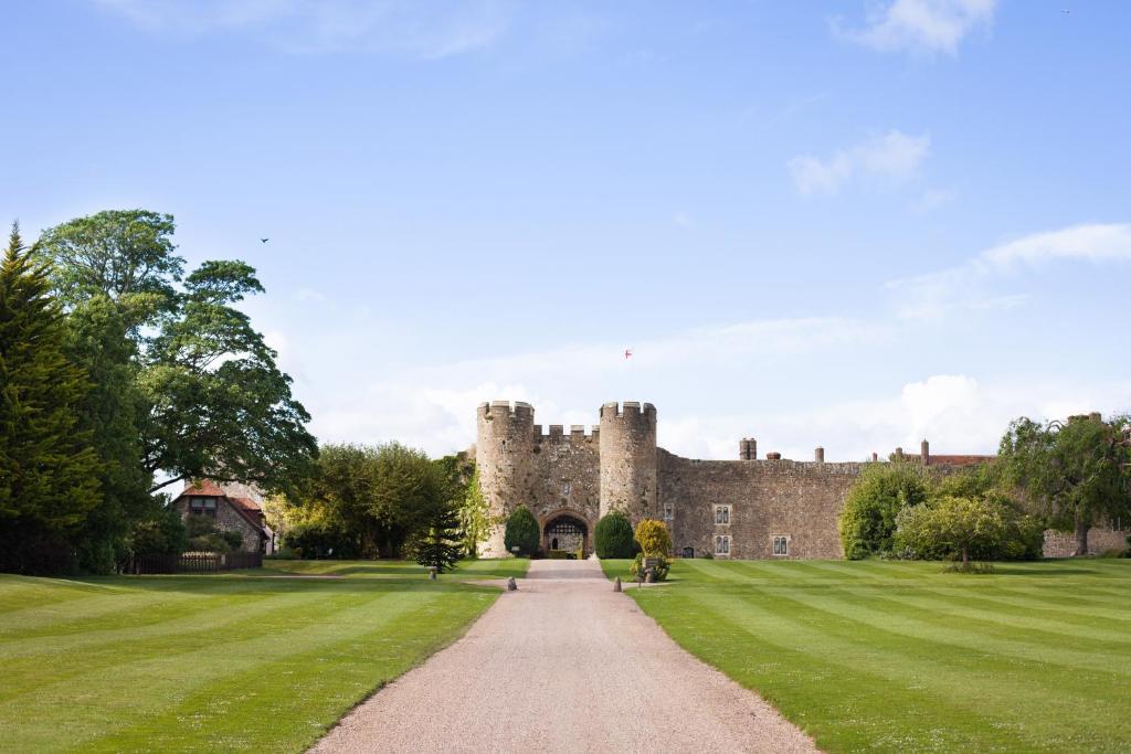 a castle with a grass field and a dirt road at Amberley Castle- A Relais & Chateaux Hotel in Amberley