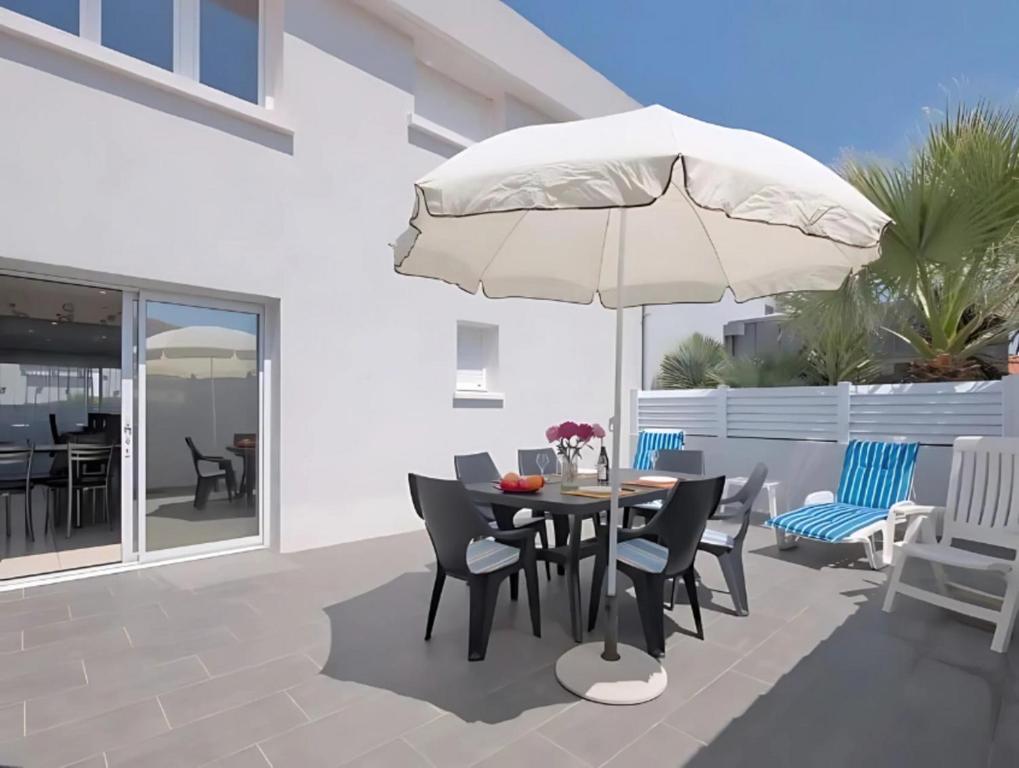 un patio avec une table et un parasol dans l'établissement Maison de vacances à 500m de la plage avec stationnement, à Les Sables-dʼOlonne