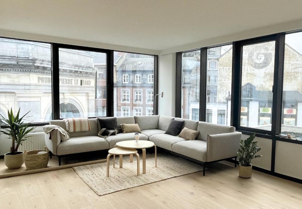a living room with a couch and a table and windows at La terrasse des sources in Spa