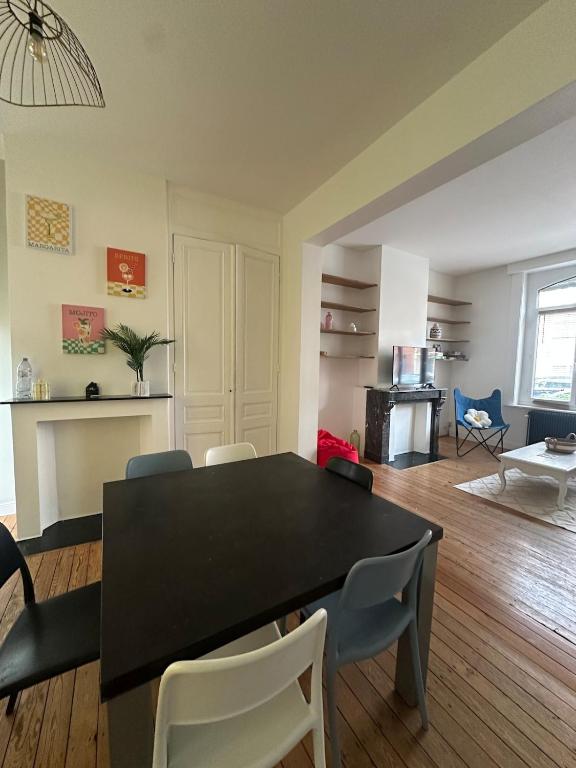 un salon avec une table et des chaises noires dans l'établissement La Malouine Dunkerquoise HomyNest, à Dunkerque