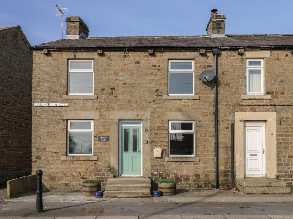 a brick house with a green door and windows at Hollywood Cottage in Barnard Castle