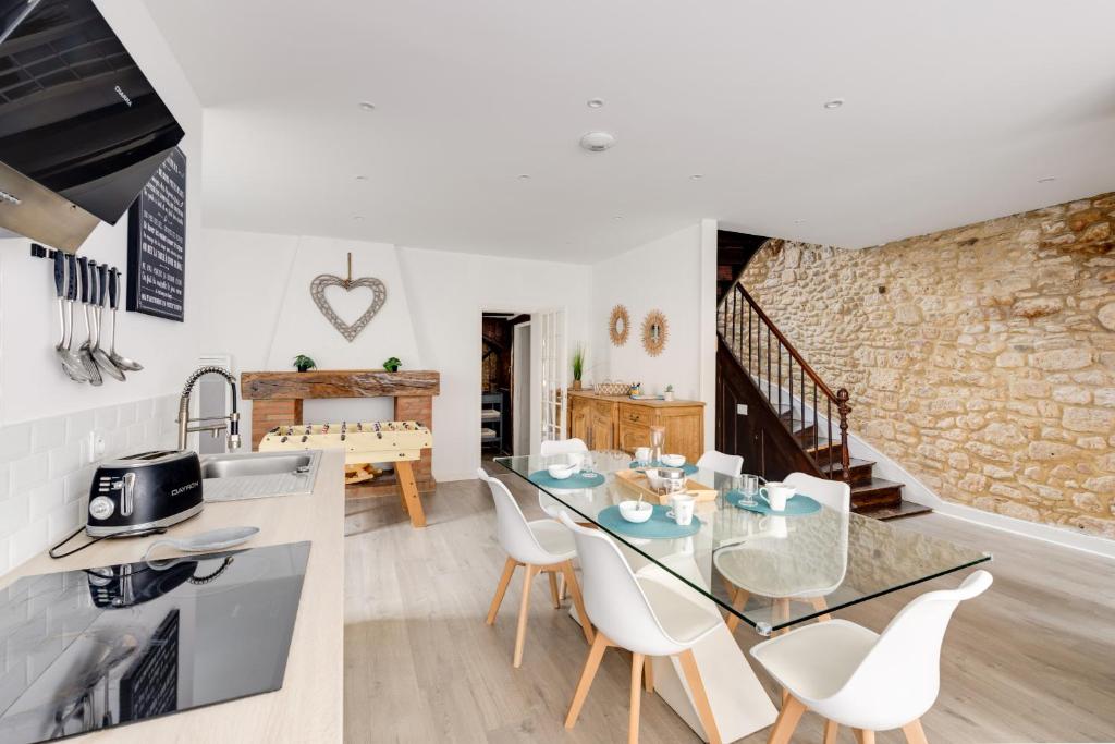 eine Küche und ein Wohnzimmer mit einem Glastisch und Stühlen in der Unterkunft Maison moderne, en pierre avec terrasse pour 6 in Montignac