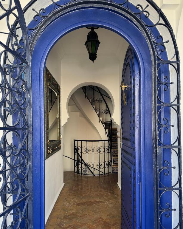an archway with a blue door and stairs at Hotel Al Alba Hammam & Restaurant in Asilah