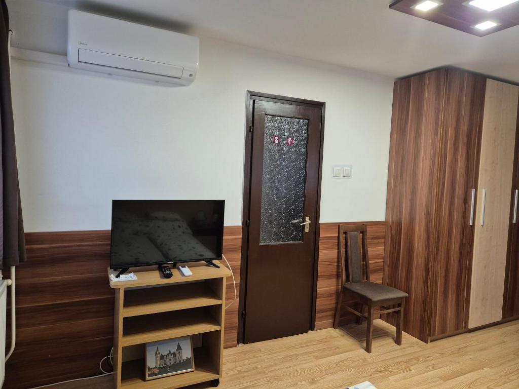 Pokój z drzwiami, telewizorem i krzesłem w obiekcie Crystal Sóstó Apartman w Nyíregyházie