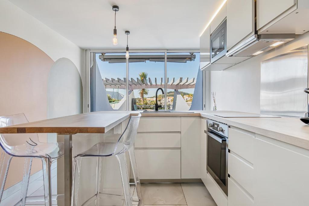 une cuisine avec des armoires blanches et une table et des chaises dans l'établissement The Wave Village Naturiste Port Ambonne Cap d Agde, au Cap d'Agde