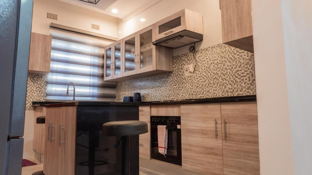 a kitchen with wooden cabinets and a stove at Siesta Apartments in Lusaka