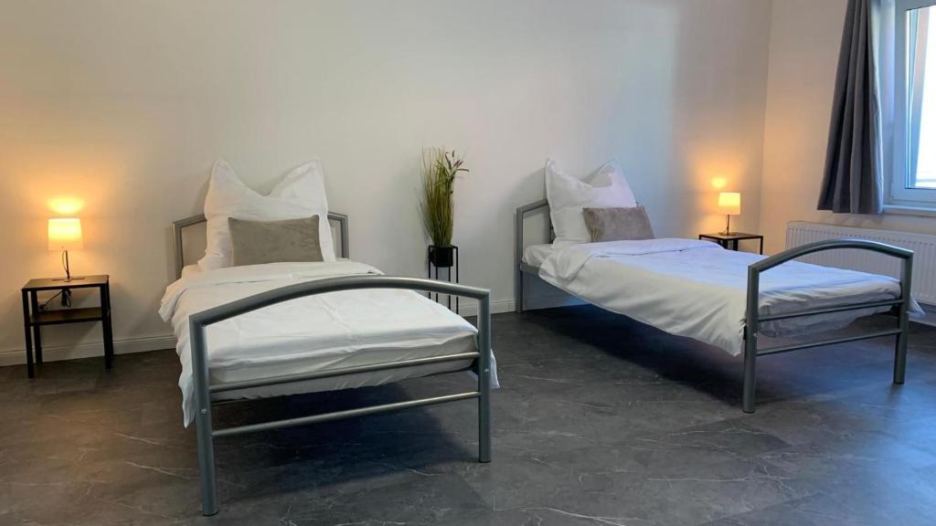 two beds in a room with two chairs and lamps at Zimmervermietung Itzehoe in Itzehoe