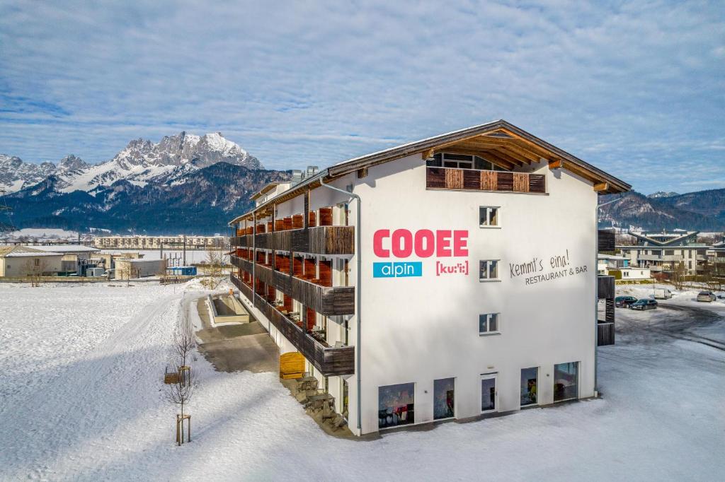 サンクト・ジョアン・イン・チロルにあるCOOEE alpin Hotel Kitzbüheler Alpenの雪の中に看板のある建物