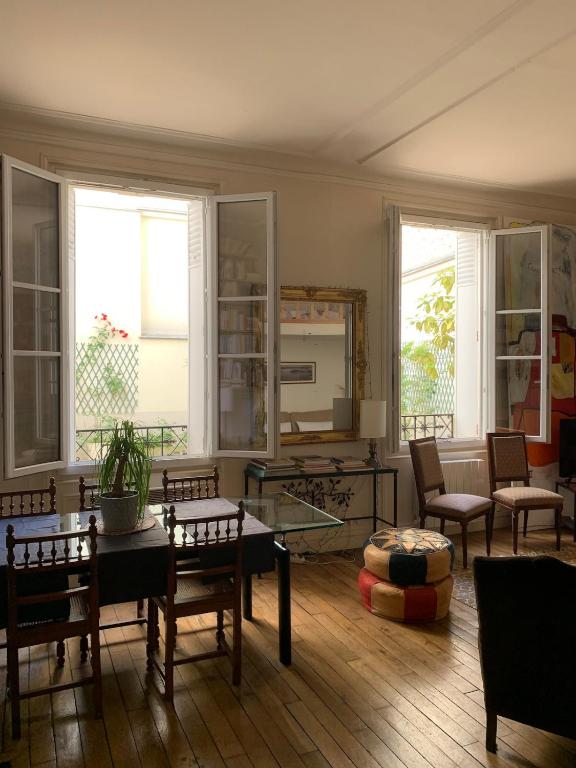 un salon avec des chaises, une table et des fenêtres dans l'établissement Eiffel Tower - Quiet, charming apartment - 2 prs, à Paris