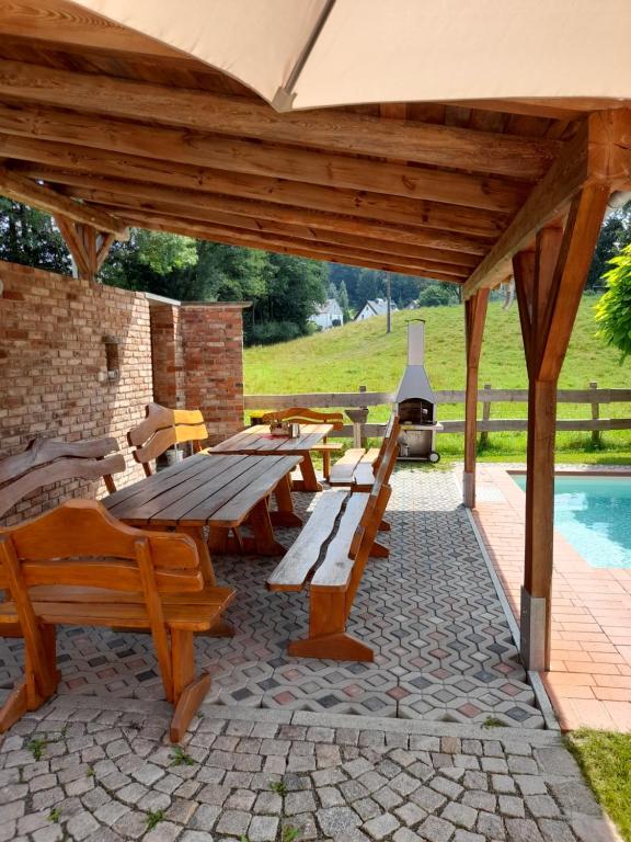 Una mesa de picnic y bancos debajo de un pabellón con parrilla. en Ferienwohnung mit 3 Schlafzimmern im Vogtland, en Heinsdorfergrund