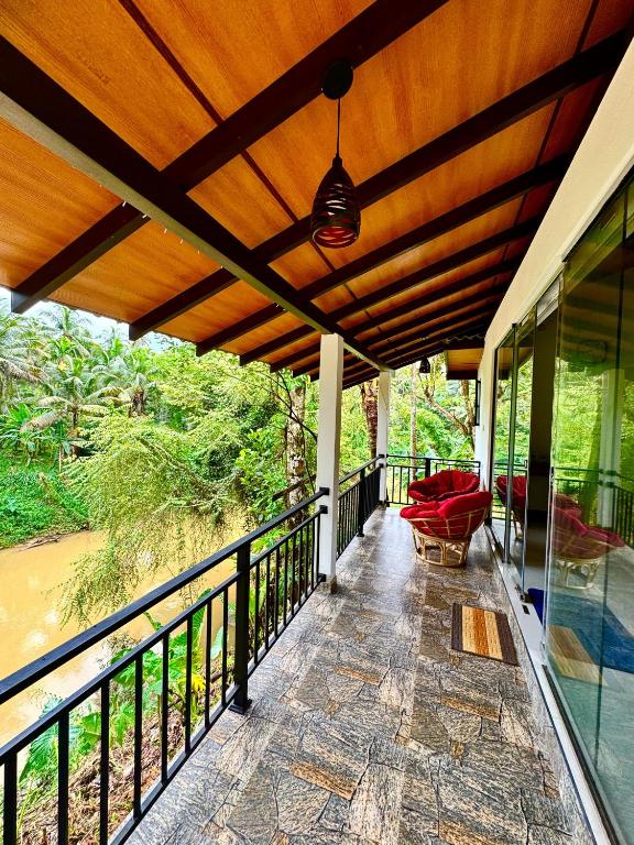 a balcony of a house with a wooden roof at Rainforest River Bay in Deniyaya