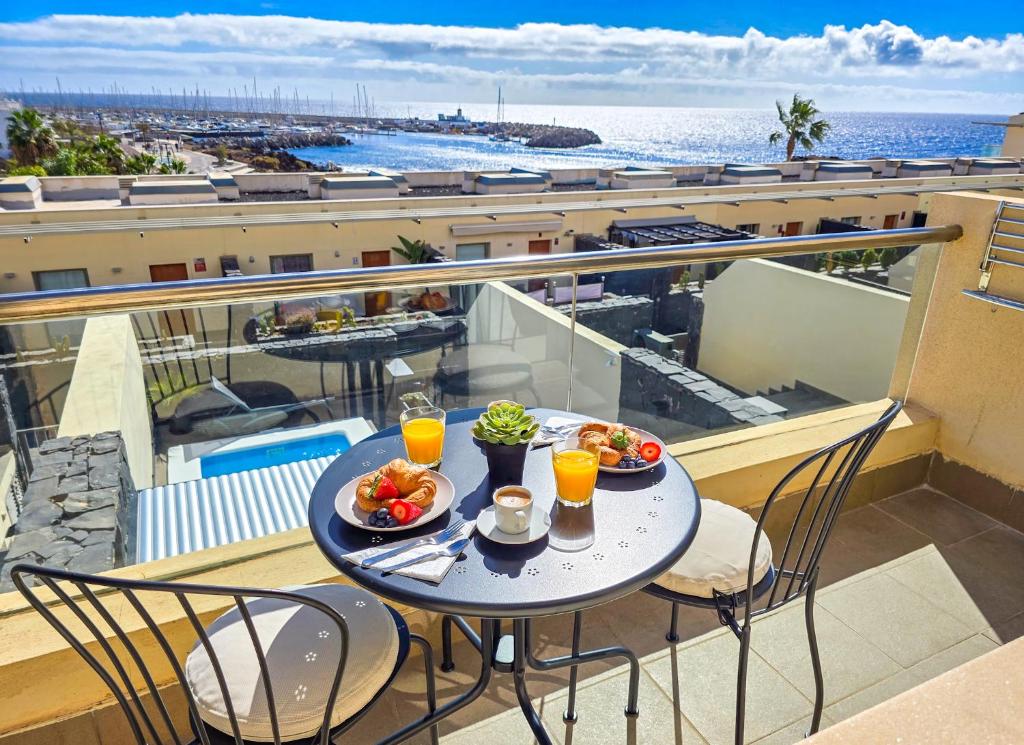 einen Tisch mit Speisen auf einem Balkon mit Meerblick in der Unterkunft Pearl of Amarilla Golf - Luxury 3 Bedroom Villa with heated pool & ocean view in San Miguel de Abona