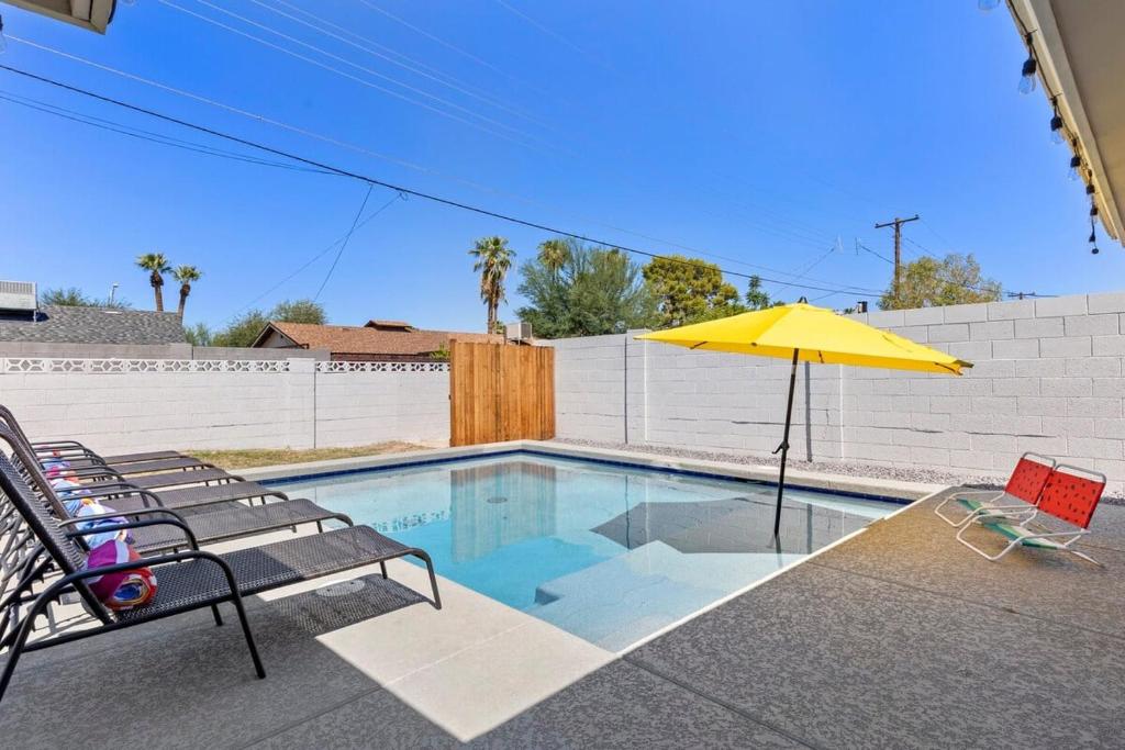 a swimming pool with a yellow umbrella and chairs at Minnezona in Scottsdale