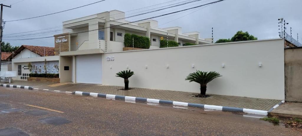 a white building with two palm trees in front of it at White River in Boa Vista