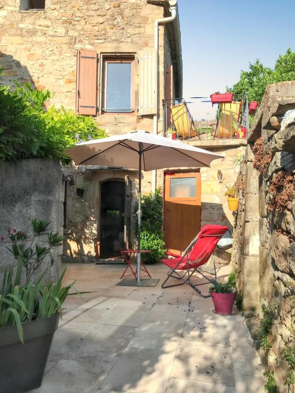 d'une terrasse avec un parasol et une chaise rouge. dans l'établissement Maison conviviale avec jardin à Saint-Privat, à Saint-Privat
