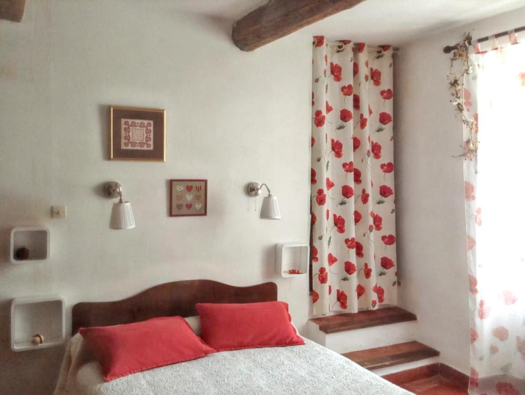una camera da letto con un letto con cuscini rossi e una finestra di Maison chaleureuse à Saint-Privat, 80 m² avec cour. a Saint-Privat