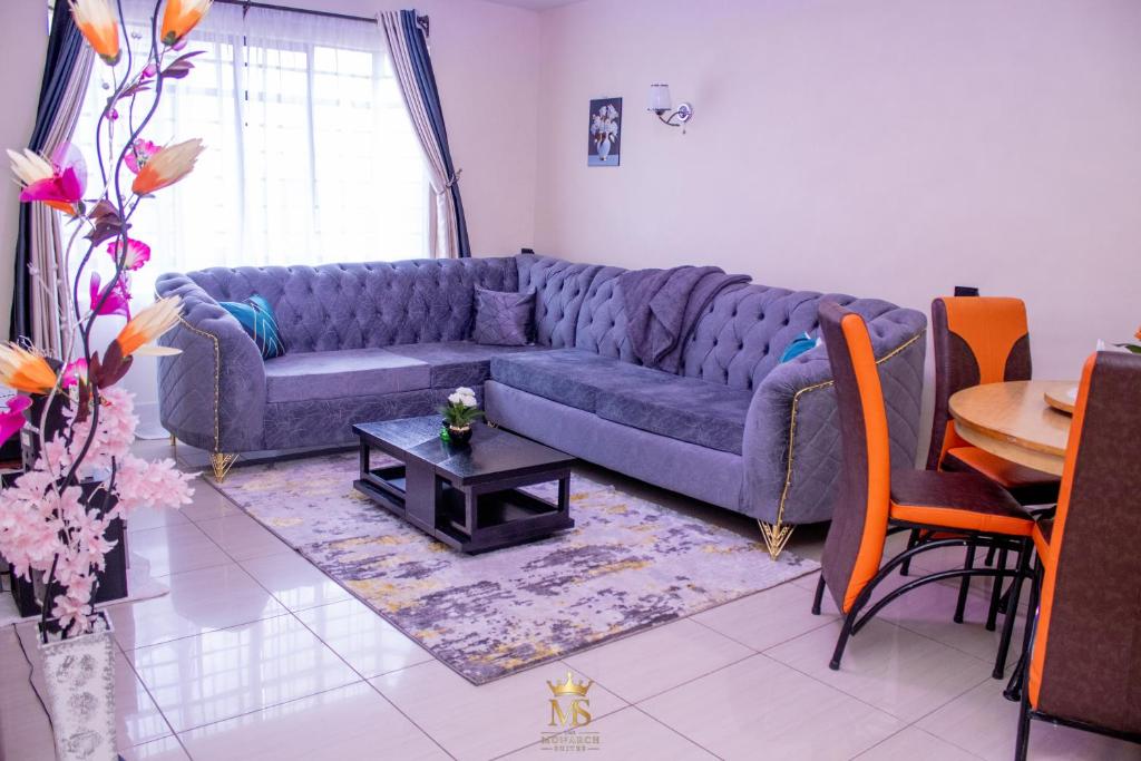 a living room with a blue couch and a table at The Monarch Suites- Peaceful Luxe 2BR with view in Nakuru
