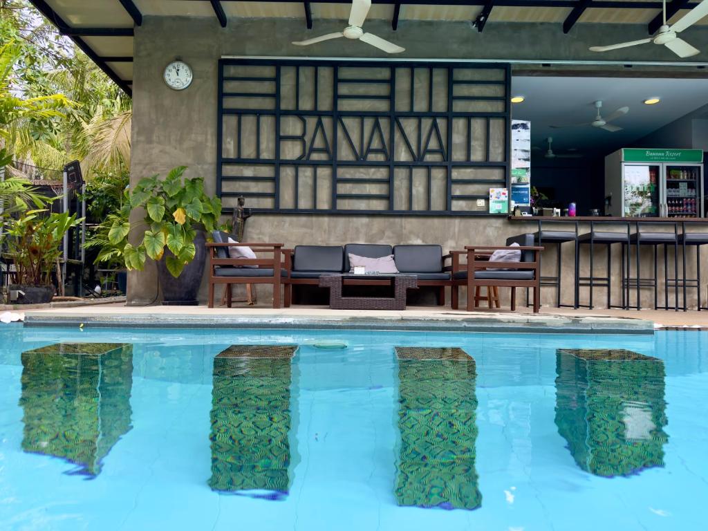 a pool in a hotel with chairs and a bar at Le petit nid Banana resort in Phumĭ Réach Born
