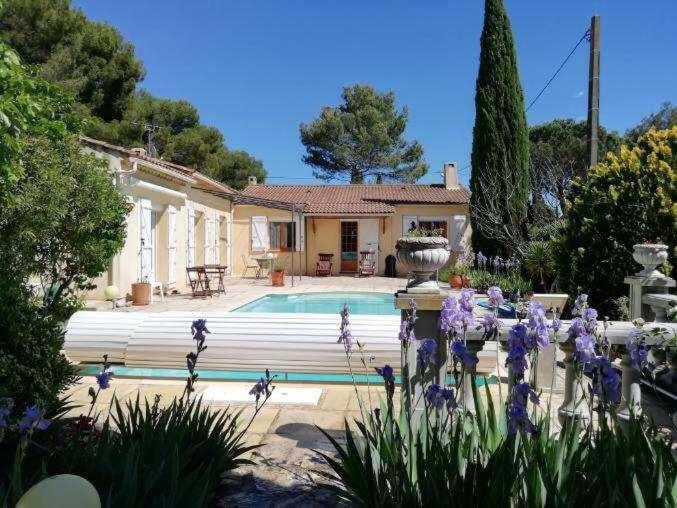 une maison avec une piscine et des fleurs en face de celle-ci dans l'établissement Maison provençale familiale avec piscine - 6 personnes, à Lambesc