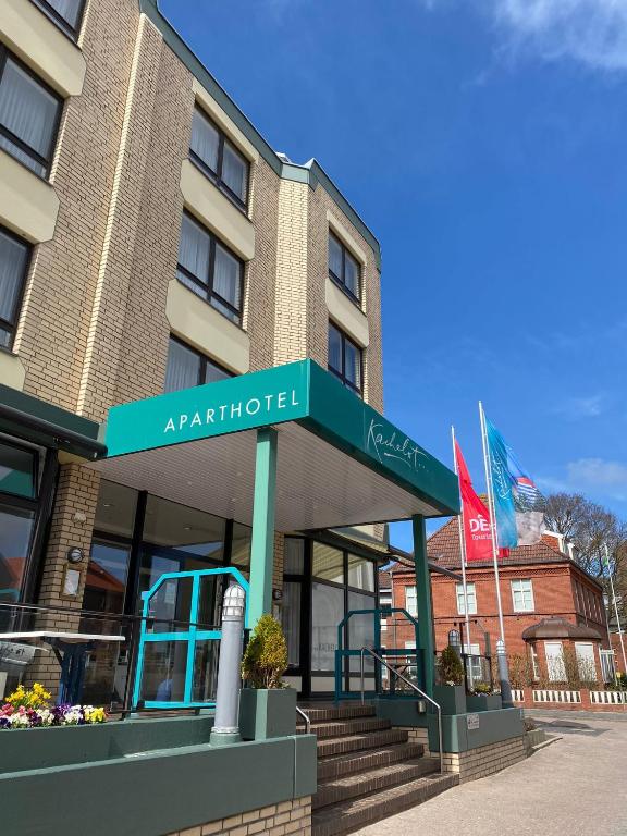 an apartment building with a green awning in front of it at Aparthotel Kachelot in Borkum