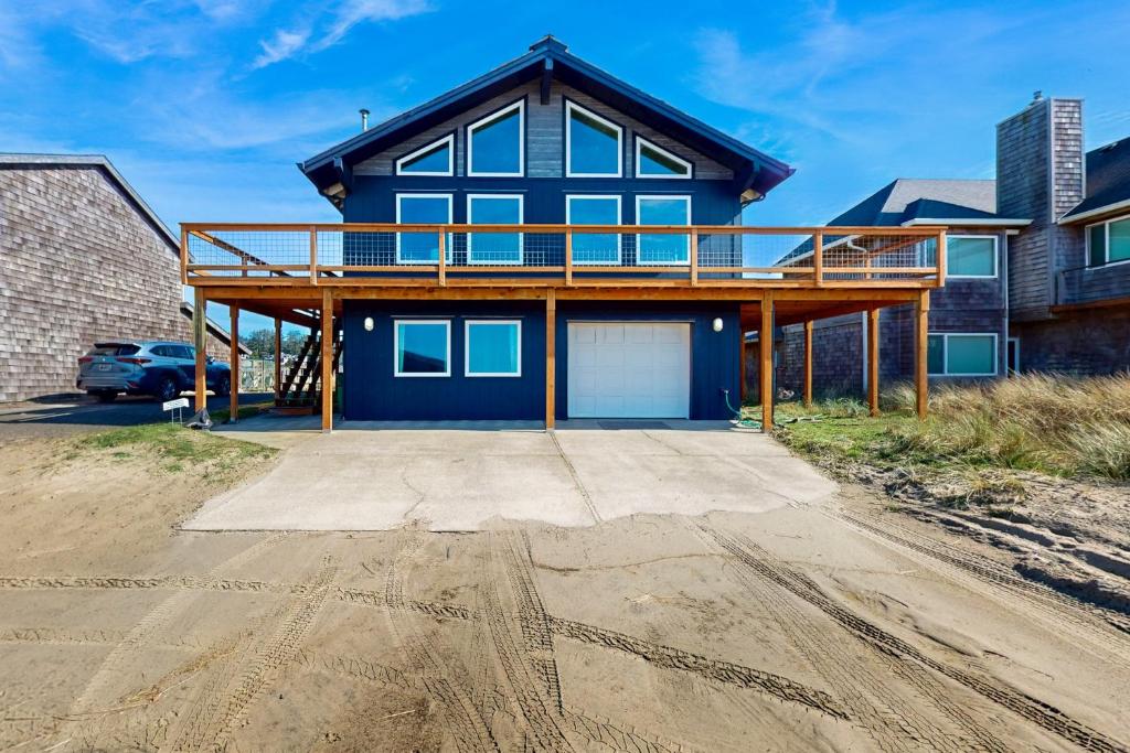 a blue house with a deck on a dirt road at The Kiwanda Surf House in Pacific City