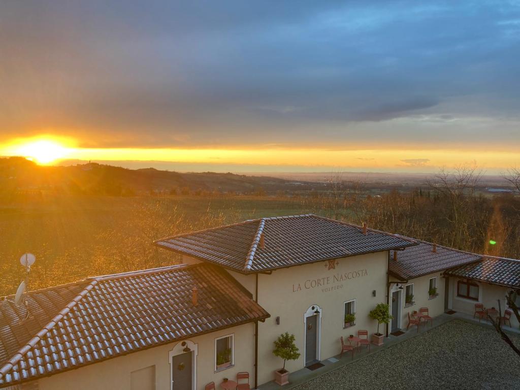 a building with the sunset in the background at La Corte Nascosta Volpedo in Volpedo