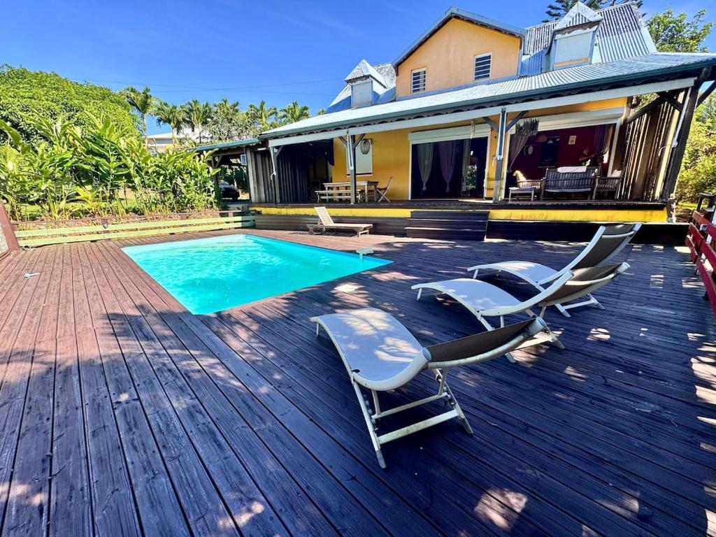 Una terraza con tumbonas y una piscina. en Villa créole et cadre tropical, en Petit-Bourg