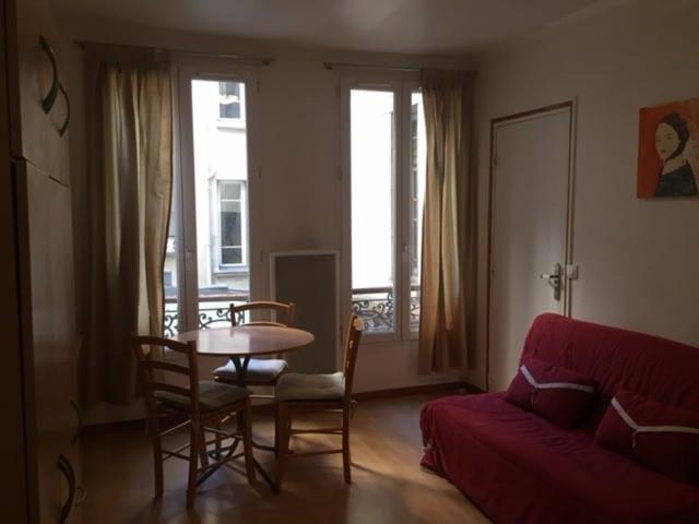 un salon avec une table et un canapé rouge dans l'établissement IB Saint Martin, à Paris