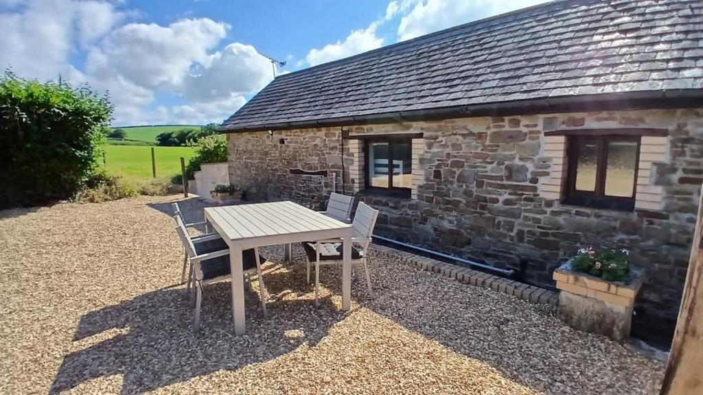 einen Tisch und Stühle vor einem Cottage aus Stein in der Unterkunft Hazel Cottage, Frithelstock in Frithelstock