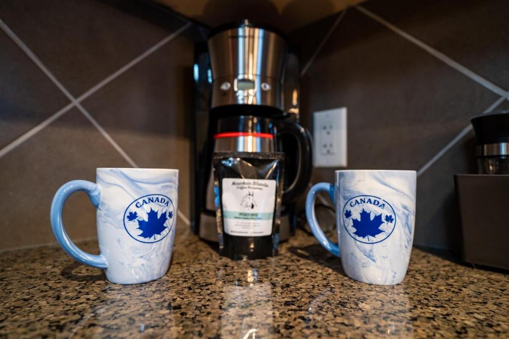 tre tazze da caffè sedute su un bancone con un frullatore di The Raven Suite at Stoneridge Mountain Resort a Canmore