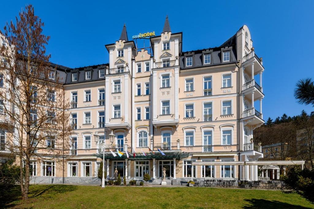 duży biały budynek w parku w obiekcie Sun Palace Wellness Hotel w Mariańskich Łaźniach