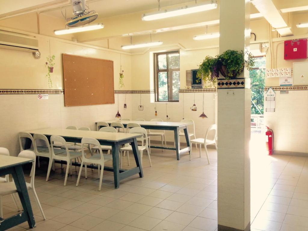 una classe con tavoli, sedie e lavagna di YHA Ngong Ping SG Davis Youth Hostel a Hong Kong