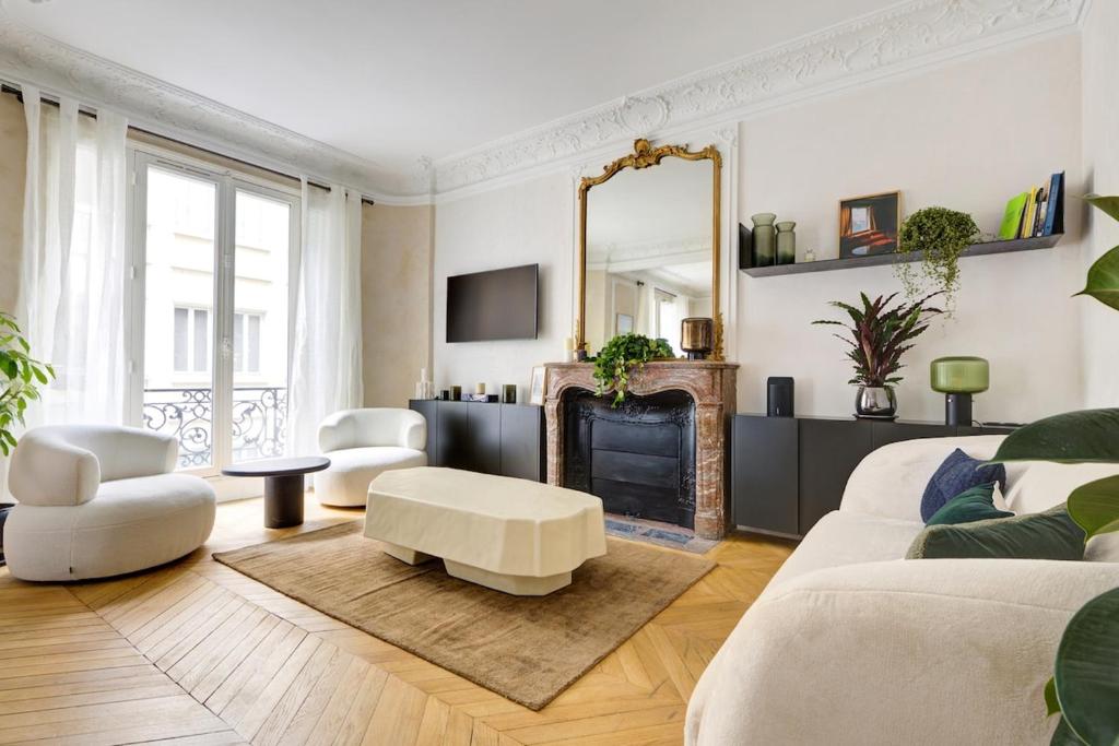 Elle comprend un salon doté d'un mobilier blanc et d'une cheminée. dans l'établissement Prestige Marais XL, à Paris