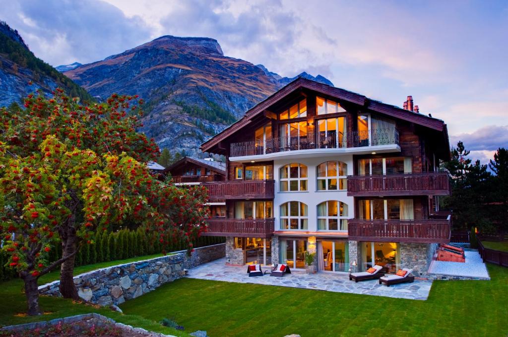 ein großes Haus mit einem Berg im Hintergrund in der Unterkunft Alex Lodge Private Luxury Apartments in Zermatt