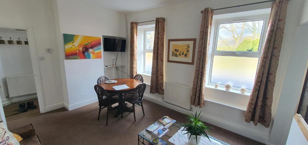 a living room with a table and two windows at Station Cottage Hawes in Hawes