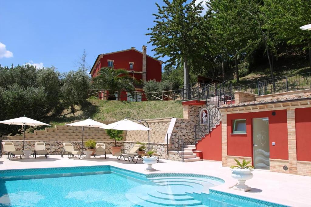 Una piscina con sillas y sombrillas al lado de una casa. en Ferienhaus Casa Sacciofa In Monte Rinaldo, en Monte Rinaldo