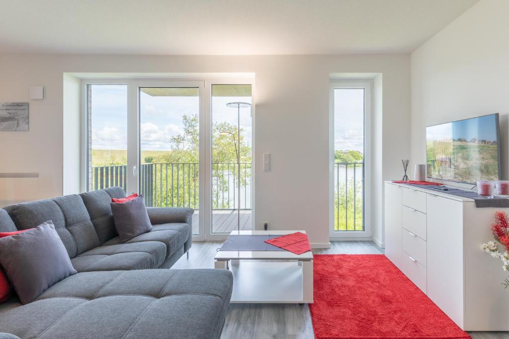 a living room with a gray couch and a red rug at Auszeit am Deich in Nordstrand
