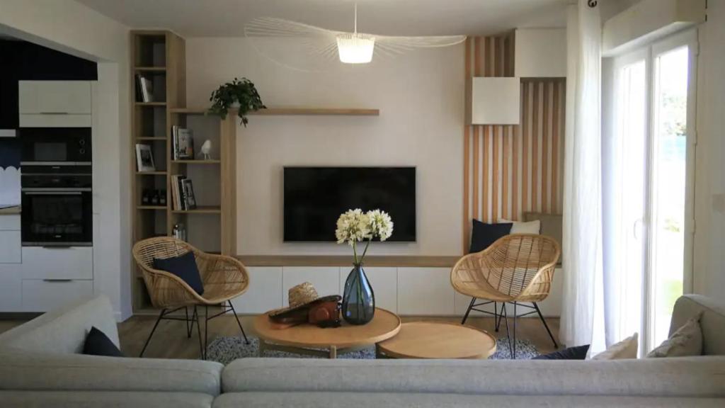 un salon avec un canapé, des chaises et une télévision dans l'établissement La maison de landrellec, à Pleumeur-Bodou