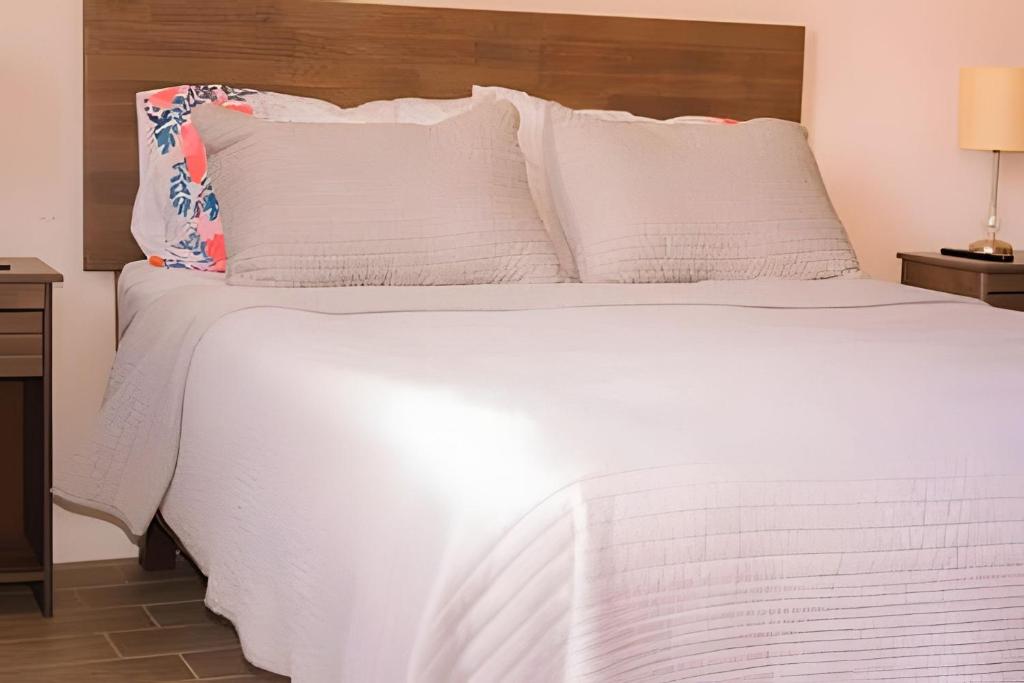 a white bed with white sheets and pillows at Tranquilo Departamento Frente al Movistar Arena in Santiago