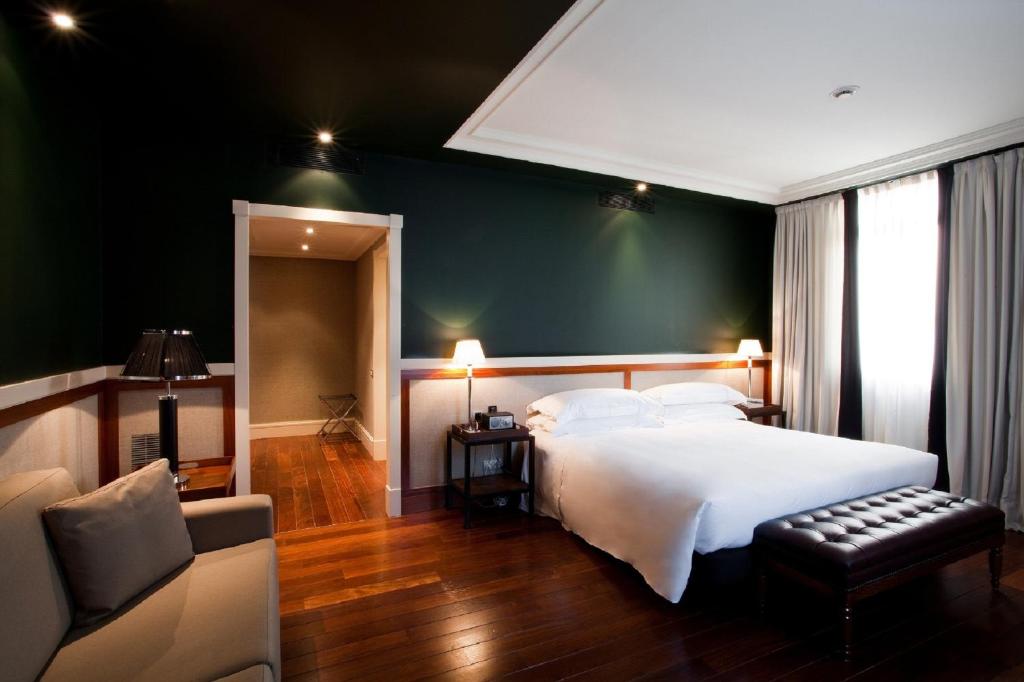 a bedroom with a large white bed and a couch at Hotel 1898 in Barcelona