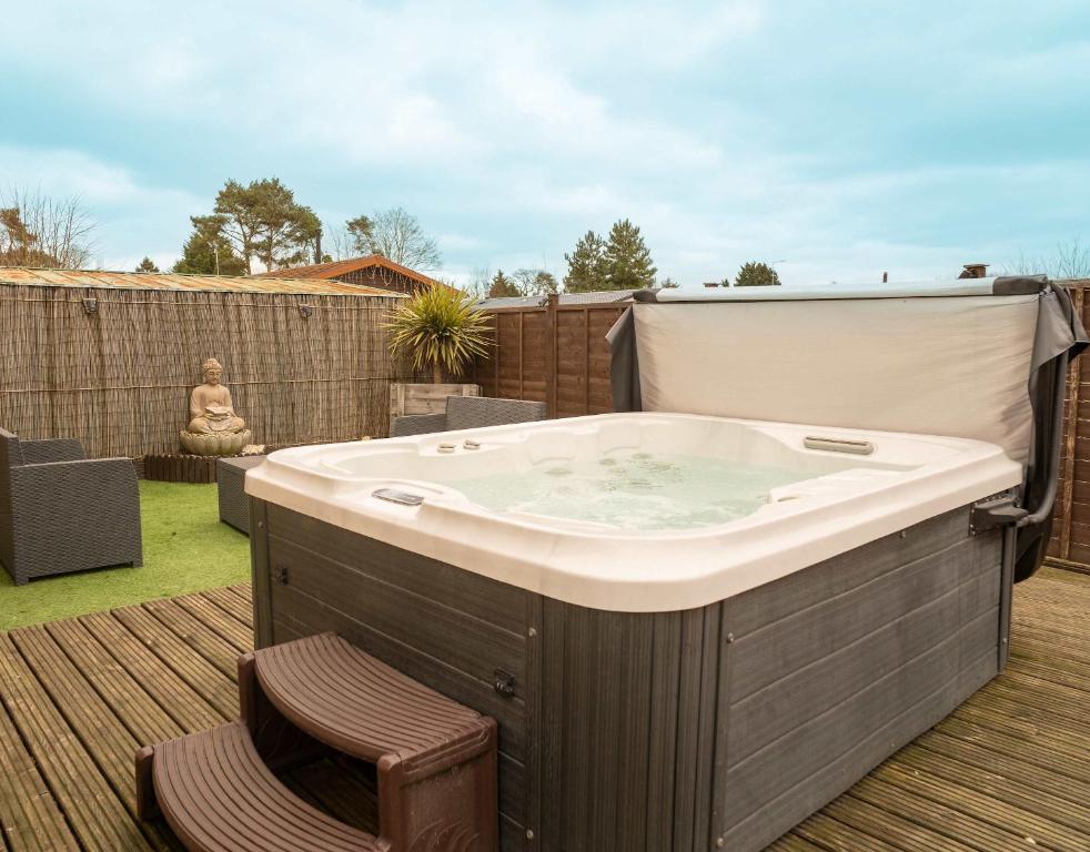une baignoire jacuzzi sur une terrasse dans une cour dans l'établissement Nualas Lodge Private Hot Tub Escape, à Wilberfoss
