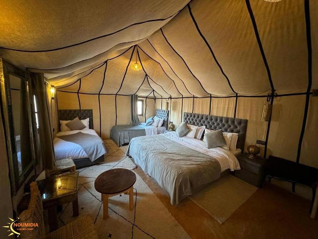 a bedroom with two beds in a tent at Noumidia Luxury Camp in Merzouga