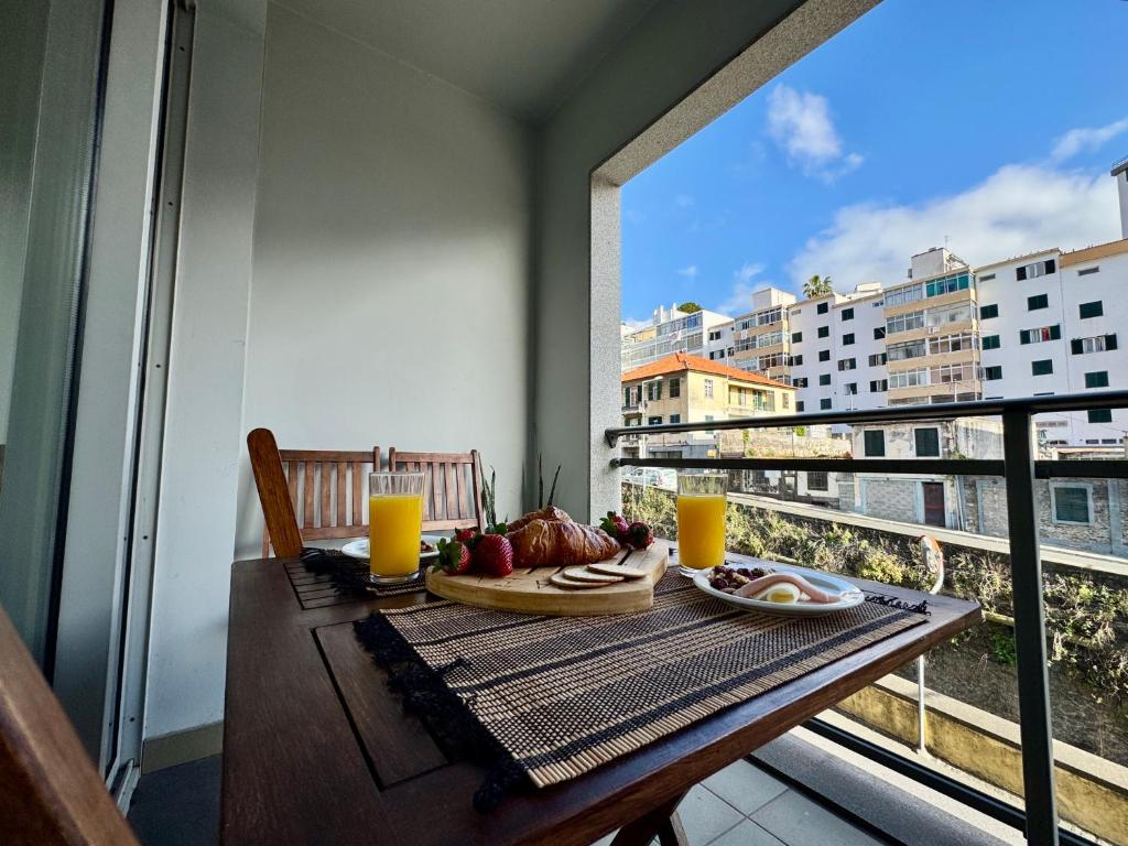 een tafel met een bord eten op een balkon bij Madeira Emotions Apartments in Funchal